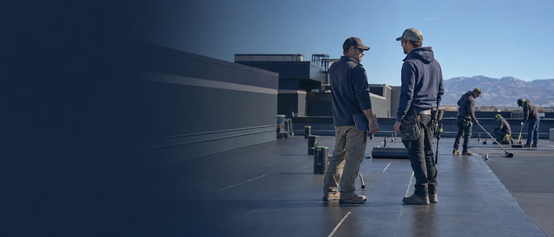 Roofing crew reviewing a job on-site with Colorado mountains in the background